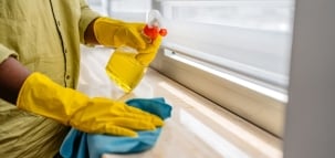 Cleaning a window sill with yellow gloves